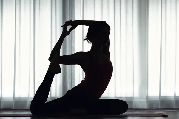 Silhouette of sporty young woman practicing yoga indoors — Stock Photo, Image