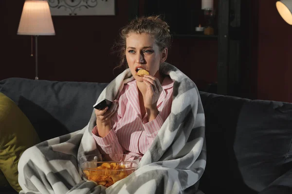 Красива молода жінка їсть нездорову їжу під час перегляду телевізора вночі — стокове фото
