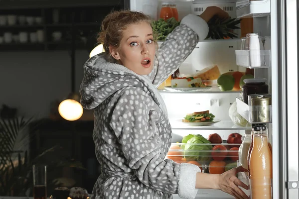 夜の冷蔵庫でおいしい食べ物を選ぶ行為に巻き込まれた恐怖の女性 — ストック写真