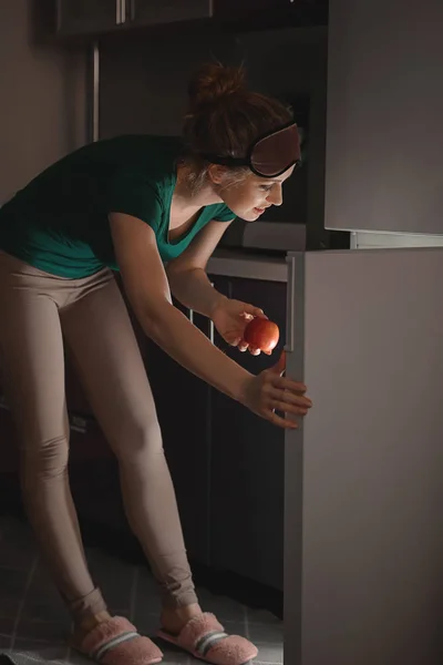 Hermosa joven mujer eligiendo comida en el refrigerador por la noche —  Fotos de Stock