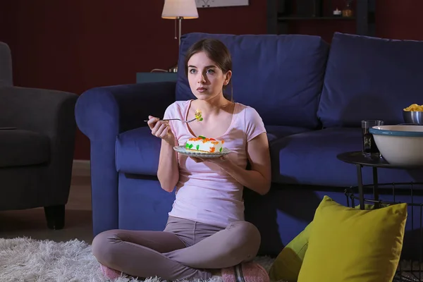 Hermosa mujer joven comiendo comida malsana por la noche — Foto de Stock