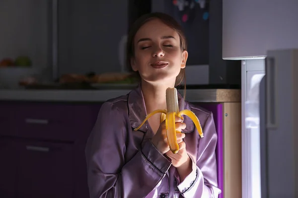 Щаслива молода жінка їсть їжу біля холодильника вночі — стокове фото