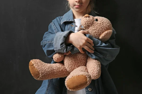 Бездомна дівчинка з плюшевим ведмедем на темному тлі — стокове фото