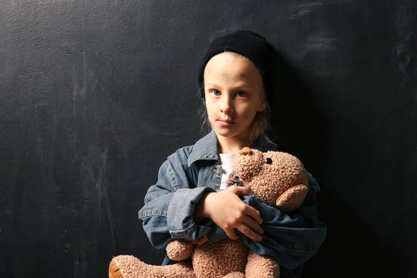 Kleines obdachloses Mädchen mit Teddybär auf dunklem Hintergrund — Stockfoto