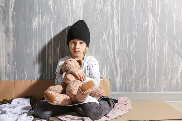 Dakloos meisje met teddybeer zittend op de vloer in de buurt van de muur — Stockfoto