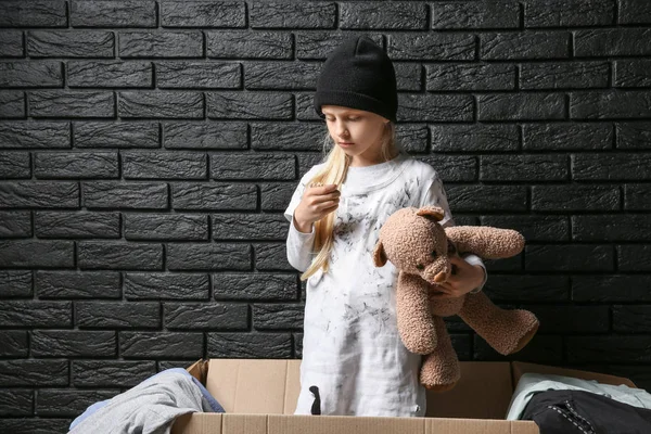 Dakloos meisje met teddybeer in de buurt van bakstenen muur — Stockfoto