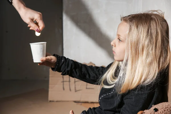 Mujer dando dinero a una niña sin hogar en el interior — Foto de Stock