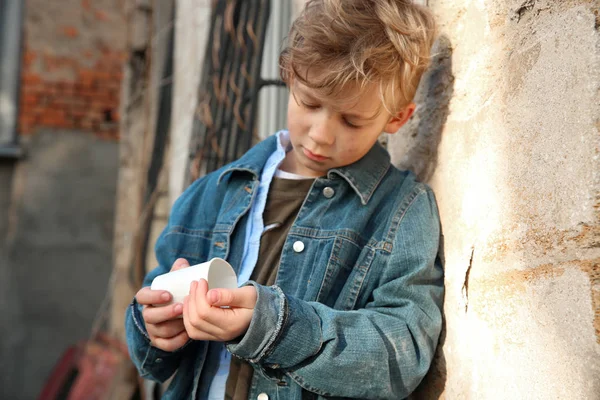 Бездомный маленький мальчик считает деньги на улице — стоковое фото