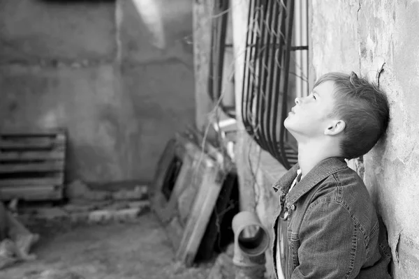 Бездомний маленький хлопчик біля стіни на відкритому повітрі — стокове фото