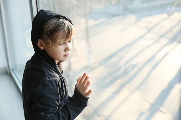 Бездомный маленький мальчик у окна — стоковое фото