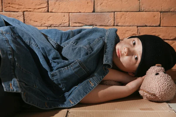 벽돌 벽 근처 바닥에 누워 테디 베어와 노숙자 작은 소년 — 스톡 사진