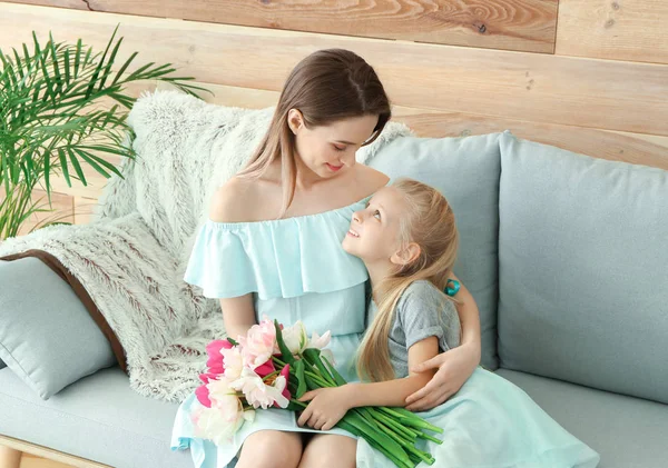 Kleines Mädchen begrüßt seine Mutter zu Hause mit einem Strauß Tulpen — Stockfoto