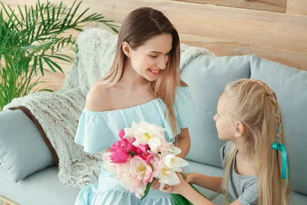 Маленькая девочка приветствует свою мать букетом тюльпанов дома — стоковое фото