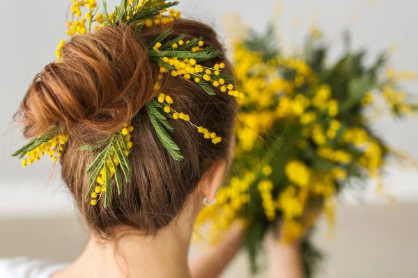 Beautiful young woman with mimosa flowers in her hair