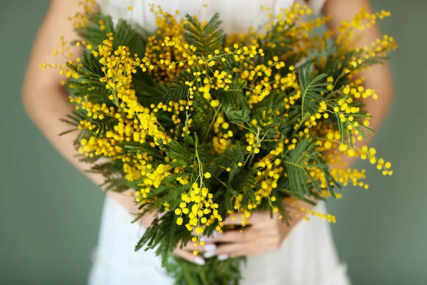 Woman with bouquet of mimosa flowers, closeup