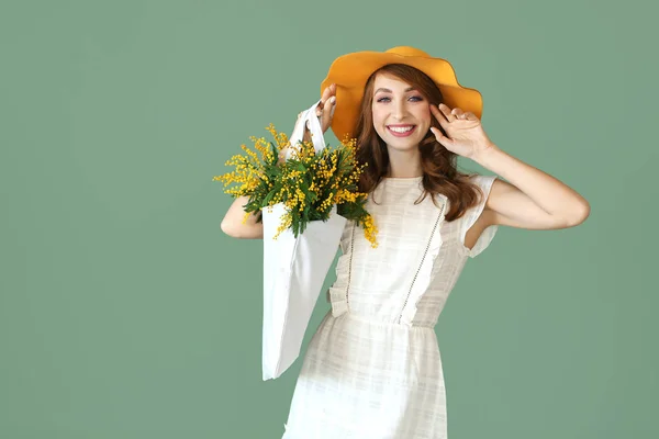 Hermosa bolsa de mujer joven con ramo de flores mimosa sobre fondo de color —  Fotos de Stock
