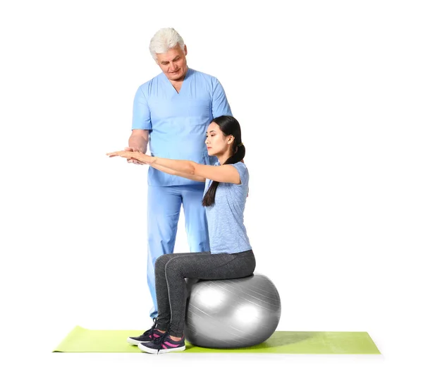 Mature physiotherapist working with young Asian woman on white background — Stock Photo, Image