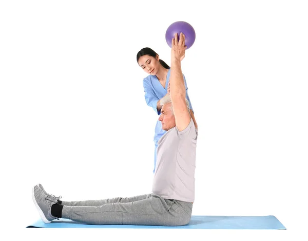 Young Asian physiotherapist working with mature man on white background — Stock Photo, Image