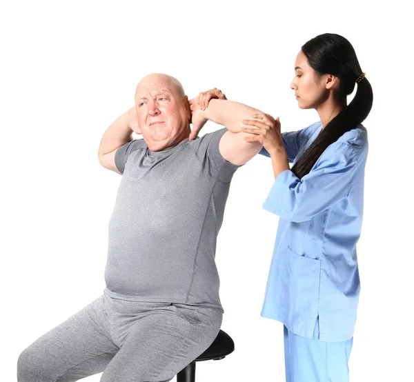 Fiatal ázsiai fizioterápiás dolgozó idős férfi fehér háttér — Stock Fotó