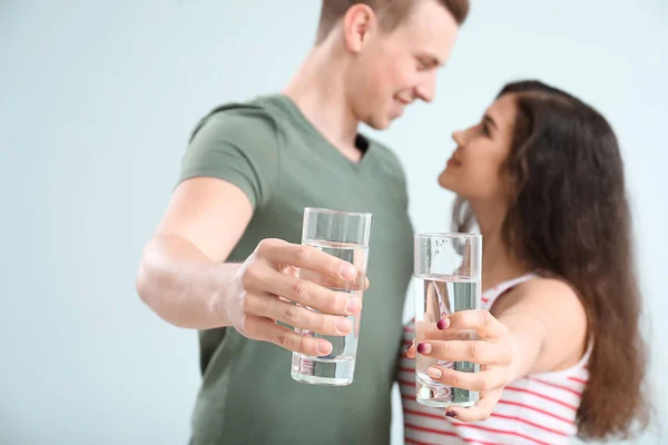 Young couple with glasses of water on light background — Stock Photo, Image