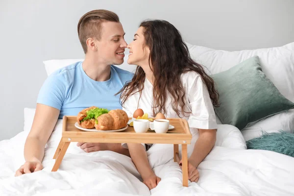 Bonito jovem casal tomando café da manhã na cama — Fotografia de Stock