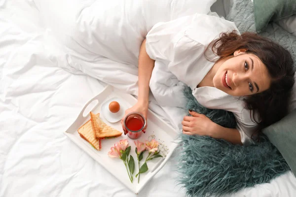 Beautiful young woman having breakfast in bed — Stock Photo, Image