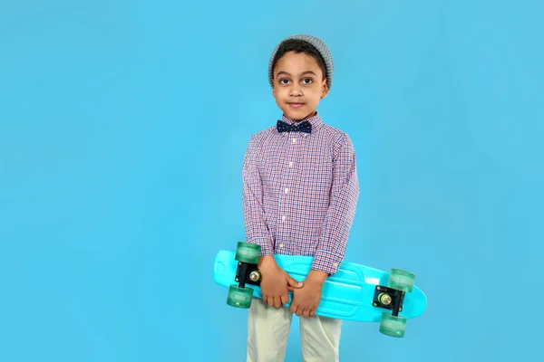 Portrait of cool little boy with skateboard on color background — Stock Photo, Image