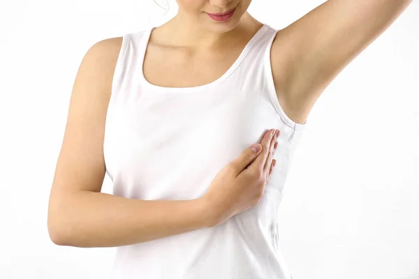 Mujer joven revisando su pecho sobre fondo blanco. Concepto de concienciación — Foto de Stock