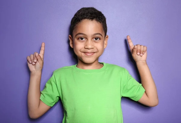 Retrato de lindo niño apuntando a algo en el fondo de color —  Fotos de Stock