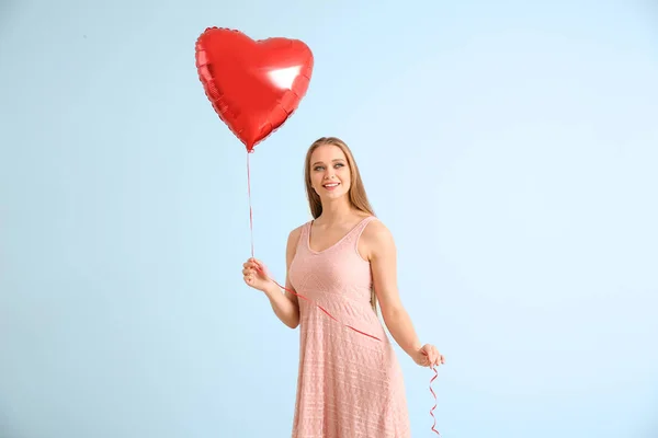 Beautiful young woman with heart-shaped air balloon on light background — Stock Photo, Image