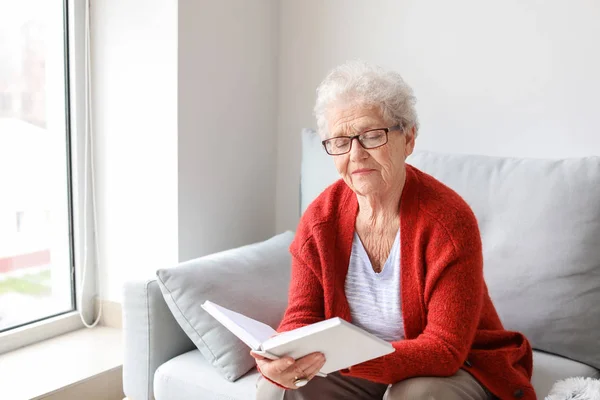 Donna anziana che legge libro a casa — Foto Stock