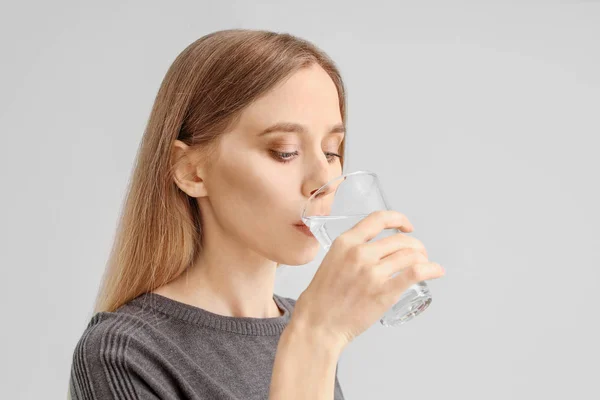 Güzel, genç bir kadın arka planda su içiyor. — Stok fotoğraf