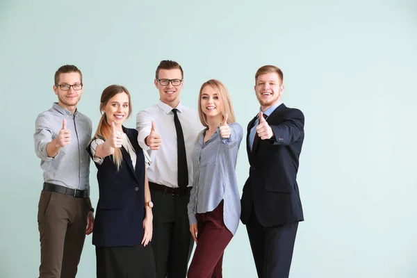 Grupp av unga affärsfolk som visar tummen upp gest på ljus bakgrund — Stockfoto