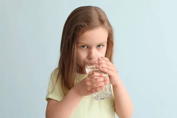 Cute little girl drinking water on light background Stock Photo