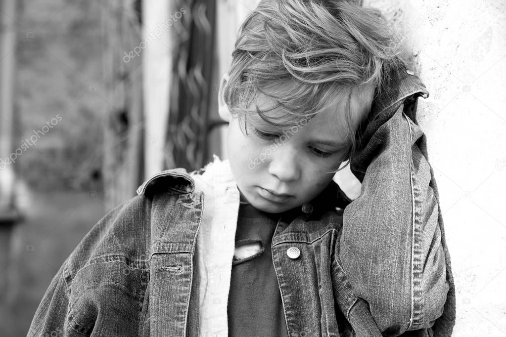 Homeless little boy near wall outdoors