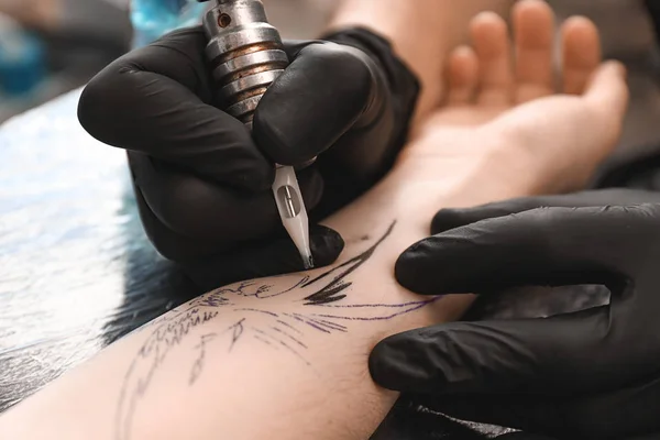 Профессиональный художник делает татуировку в салоне, крупным планом — стоковое фото