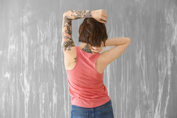 Beautiful tattooed woman near grunge wall