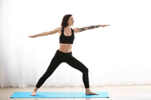 Bella donna tatuata che pratica yoga a casa — Foto Stock
