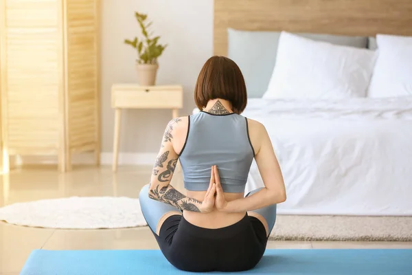 Hermosa mujer tatuada practicando yoga en casa — Foto de Stock