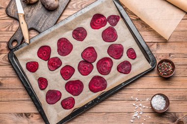 Ahşap masa üzerinde lezzetli çiğ pancar cipsi ile fırın tepsisi