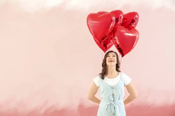 色の背景にハート型の気球を持つ美しい若い女性 — ストック写真