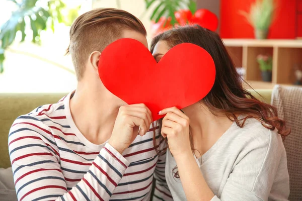 Joyeux jeune couple avec coeur en papier à la maison — Photo