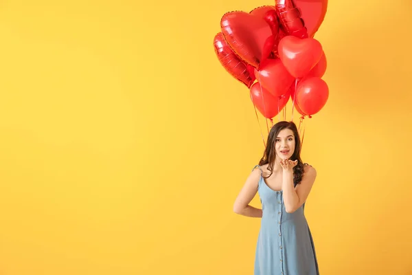 Beautiful young woman with heart shaped air balloons on color background — Stock Photo, Image