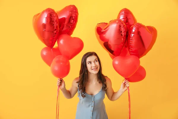 色の背景にハート型の気球を持つ美しい若い女性 — ストック写真