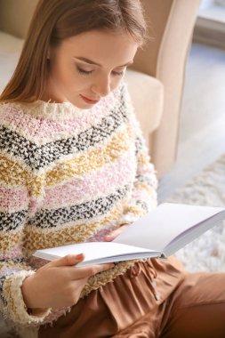 Evde kitap okuyan güzel genç bir kadın.