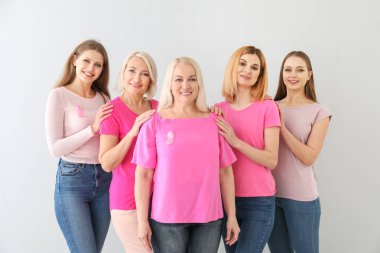 Açık arka planda pembe kurdeleler ile farklı yaşlarda güzel kadınlar. Meme kanseri kavramı