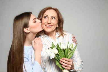 Genç kadın ışık arka planda buket ile annesini tebrik