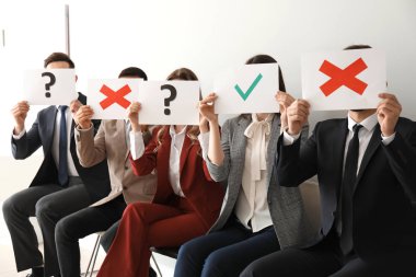 Gençler kapalı koltuklarda otururken farklı işaretler ile kağıt levhalar tutan genç insanlar. İş görüşmesi kavramı