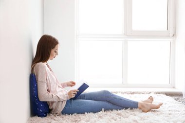 Evde kitap okuyan güzel genç bir kadın.