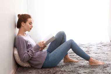 Evde kitap okuyan güzel genç bir kadın.